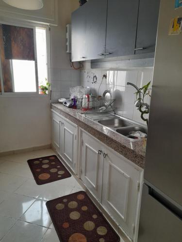 una cucina con armadi bianchi e lavandino di Nawal Tigumi ad Agadir