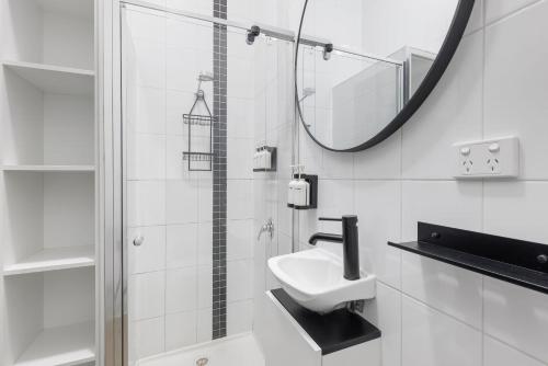 a white bathroom with a sink and a mirror at Selina Central Melbourne in Melbourne