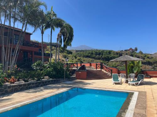 a swimming pool with two chairs and a house at Finca La Romera in La Orotava