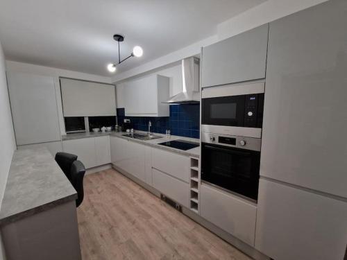 a kitchen with white cabinets and a black appliance at Newly renovated apartment! in London