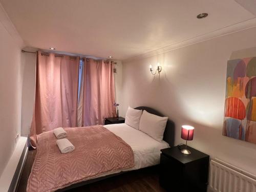 a bedroom with a bed and a window with pink curtains at Entire 2-bedroom Flat in Camden in London