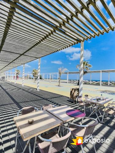 d'une terrasse avec des tables et des chaises sur la plage. dans l'établissement LA CABANE DE LA MER, à Leucate