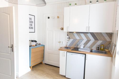 a kitchen with white cabinets and a sink at Auguste, La Romaine et My César - Location Saverne in Saverne