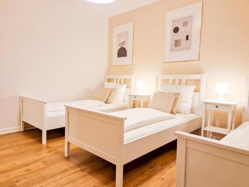 um quarto branco com duas camas e duas mesas em Apartment beim Theater em Hildesheim