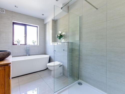 a bathroom with a tub and a toilet and a glass shower at Hewas Water House in Grampound