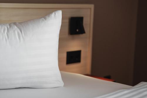 a white pillow sitting on top of a bed at Kloster by b-smart in Schaan