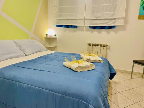 una camera da letto con un letto blu con sopra degli asciugamani di Casa Mare Naxos Flat - Home Holiday a Giardini Naxos