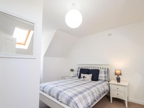 a white bedroom with a bed and a window at Taigh Tearlach in Kyleakin