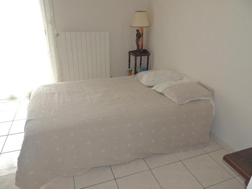 a bed with white sheets and pillows in a room at La maison du Barbot Maison 6 couchages in Gujan-Mestras