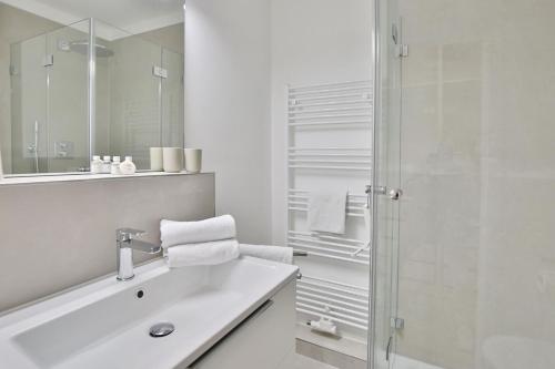 uma casa de banho branca com um lavatório e um chuveiro em Residenz am Hang Residenz am Hang Appartement 311 em Scharbeutz