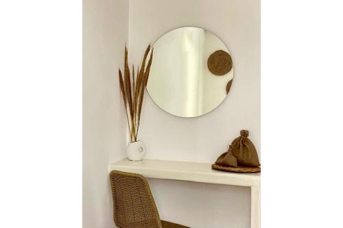 a mirror on a wall above a shelf with a chair at Cal Day Rooms Santorini in Perissa