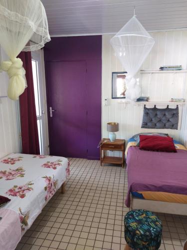 a bedroom with two beds and a purple wall at LES GÎTES DU DOMAINE DE PETITE-ANSE in Bouillante