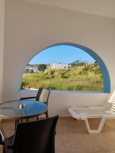 Habitación con mesa, sillas y ventana en Aggeliki's Apartments en Lipsoi