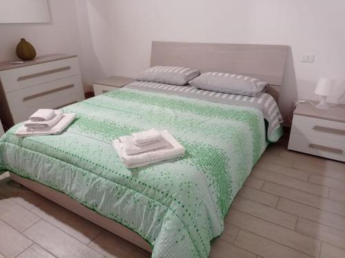 Un dormitorio con una cama verde con toallas. en Case Vacanza Villaggio Riva Azzurra, en Policoro