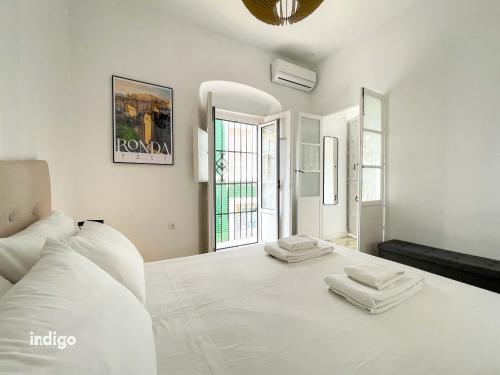 1 dormitorio blanco con 1 cama blanca grande y 2 toallas en Casa Cristóbal Colón habitaciones con vistas a Semana Santa y Fiestas en Ayamonte