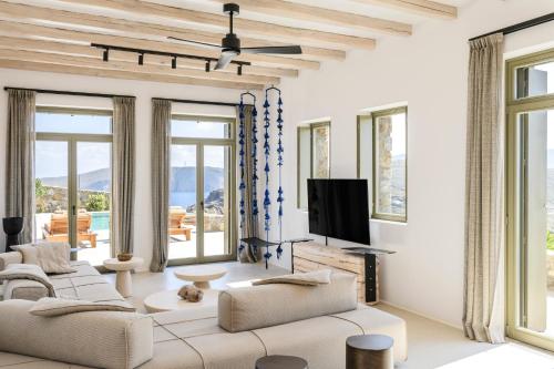 a living room with white furniture and large windows at Nasta Suites & Villas Intentional Living Mykonos in Mýkonos City