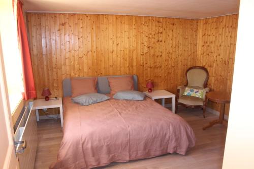 a bedroom with a bed with two tables and a chair at Chez Ginette et Jean-François in Le Chenit