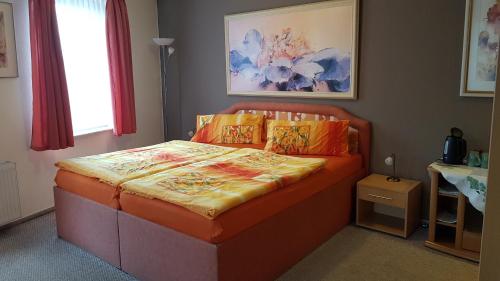 een slaapkamer met een oranje bed met oranje kussens bij Galeriecafe und Pension Ambiente in Zittau