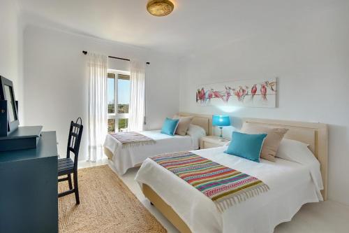 a bedroom with two beds and a desk with a tv at Casinha do Sol in Almancil