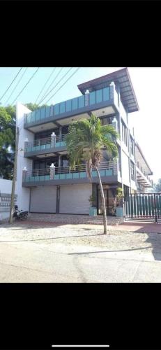 a building with a palm tree in front of it at Nober Apartments in Puerto Princesa City