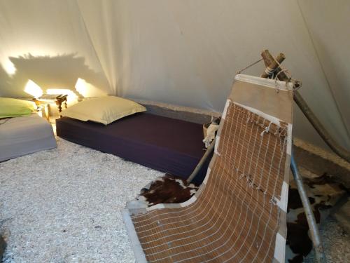 um quarto com uma cama e um banco numa tenda em Thipi Khola em Val Couesnon