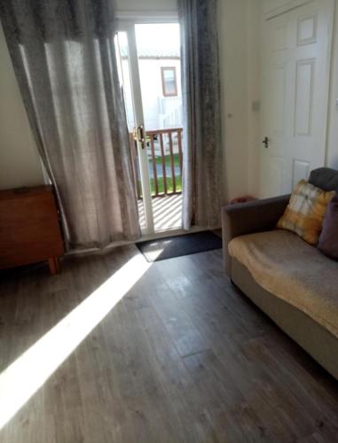 a living room with a couch and a sliding glass door at H3 Rickardos Holiday Lets in Mablethorpe