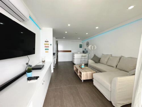 een woonkamer met een bank en een flatscreen-tv bij Apartamento Playa chica, vistas al mar Lanzarote in Puerto del Carmen