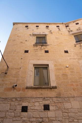 a tall brick building with three windows on it at B&B Palazzo Vittoria in Bisceglie