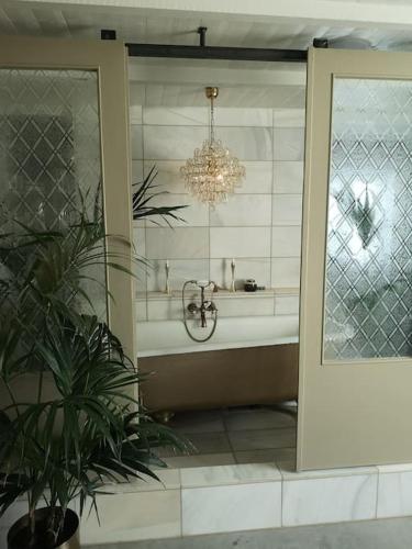 a bathroom with a bath tub and a chandelier at Mojo organic spa in Borgholm