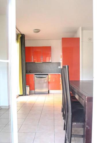 a kitchen with red cabinets and a black table and chairs at T3 dans résidence avec piscine in Six-Fours-les-Plages