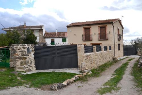 a house with a black gate and a stone wall at LA PORTADA DE ABAJO in Gallegos