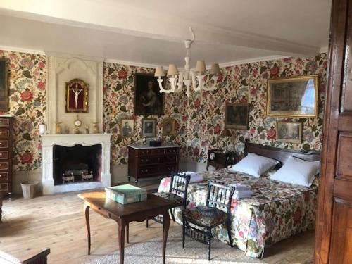 a bedroom with a bed and a table and a fireplace at Chambres d'Hôtes Le Clos de Bonneval in Saint-Jean-de-Thouars