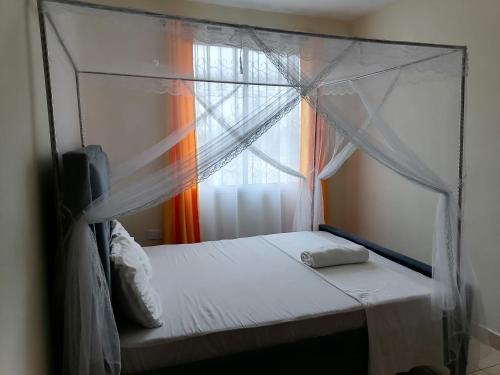 1 dormitorio con cama con dosel y ventana en La Grande 1bedroom Apartment Mtwapa, en Mtwapa