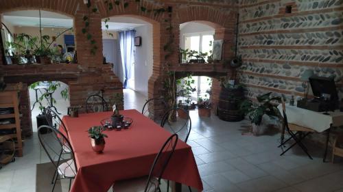 米雷的住宿－Chez Cathie à Muret，一间设有红桌和砖墙的用餐室