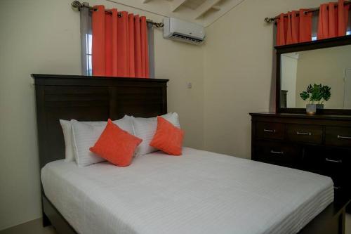 a bedroom with a bed with orange and white pillows at Entire residential home • Trelawny• Smalls Villa in Florence Hall