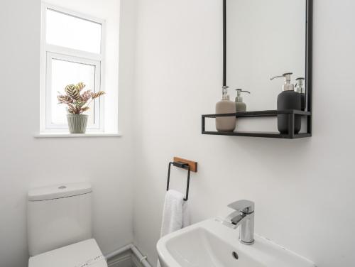 a bathroom with a sink and a toilet and a window at Gwynant - Bull Bay in Amlwch