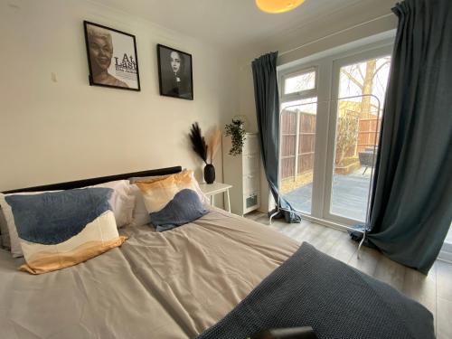 a bedroom with a bed and a large window at Stylish 4 Bedroom House with Private Parking and Free WiFi in Milton Keynes by HP Accommodation in Milton Keynes