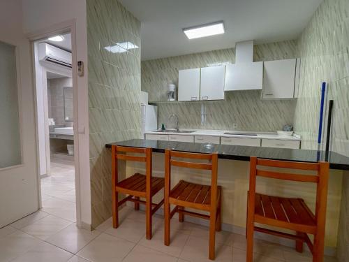 uma cozinha com 2 cadeiras e um balcão com um lavatório em Apartamentos Cel Blau em Es Cana