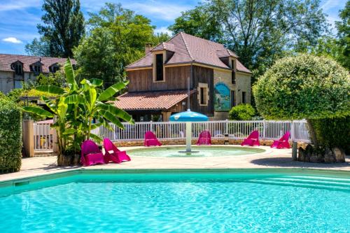 une piscine avec des chaises roses et une maison dans l'établissement Camping Le Moulin du Bleufond, à Montignac