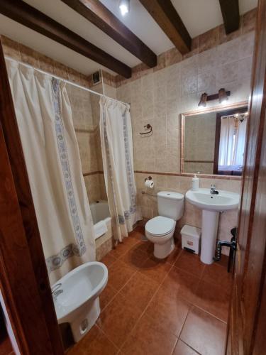 a bathroom with a toilet and a sink and a tub at Casas Rurales TIO CLAUDIO I y II in El Barraco