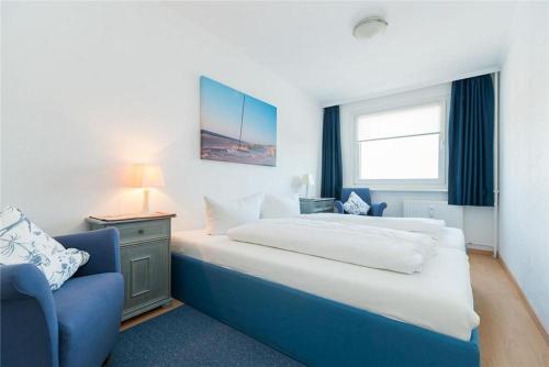 ein Schlafzimmer mit einem großen Bett und einem blauen Stuhl in der Unterkunft Haus Ankerlicht 3.OG Wohnung 43 in Westerland