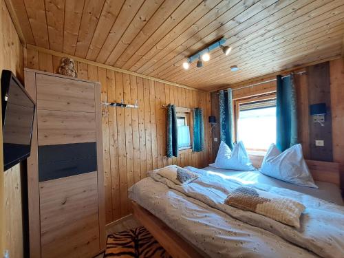 Cama en habitación de madera con ventana en Chalet Panorama Tirol en Hofen