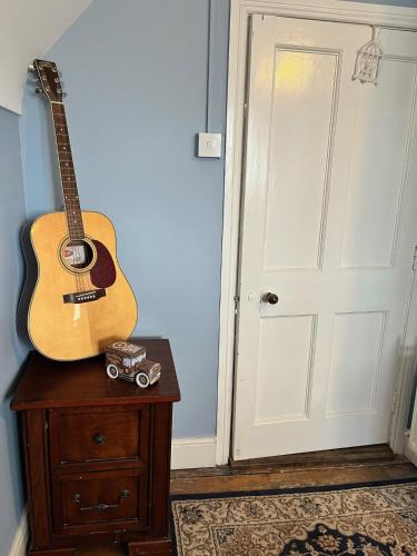 a guitar sitting on top of a wooden table next to a door at Stone Lodge B&B in Balrath