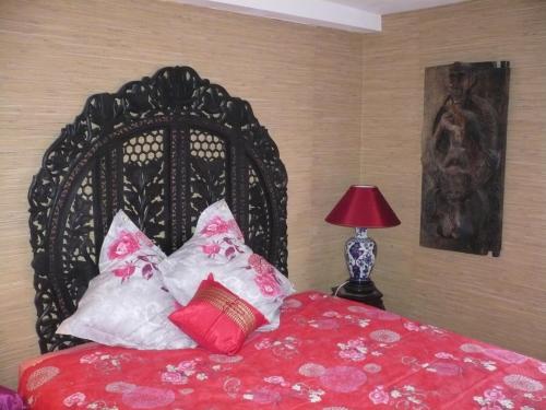 a bedroom with a black bed with red sheets and pillows at Le Havre de Bennecourt in Bennecourt