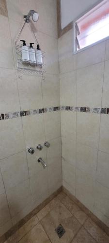 a bathroom with a shower with three bottles in it at Depto de La Lila in Salta