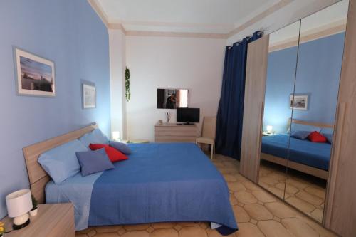 een slaapkamer met een blauw bed en een spiegel bij Il vecchio bastione in Aci Castello