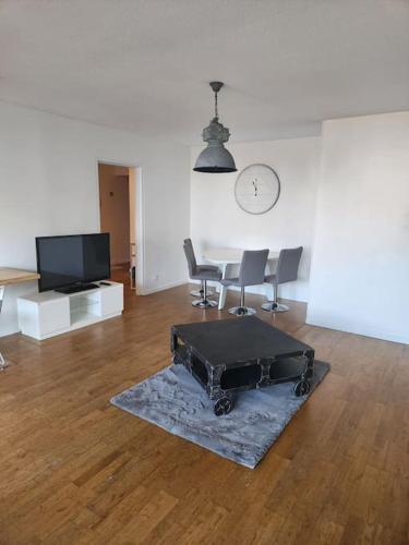 - un salon avec une table, des chaises et une horloge dans l'établissement Appartement T4 très spacieux, à Grenoble