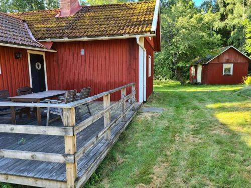 a red house with a wooden deck next to a building at Trevligt Torp i vacker natur in Mellerud