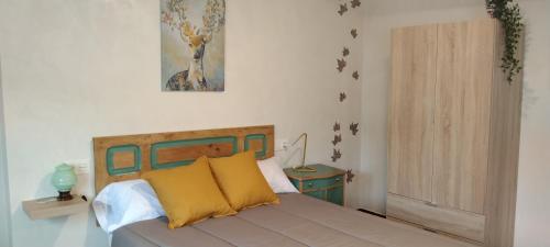 a bedroom with a bed with yellow pillows at El Volante Alojamiento Turístico in Villafranca del Bierzo