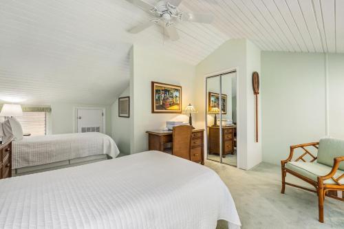 a white bedroom with two beds and a chair at Spectacular golf course front in Kahuku